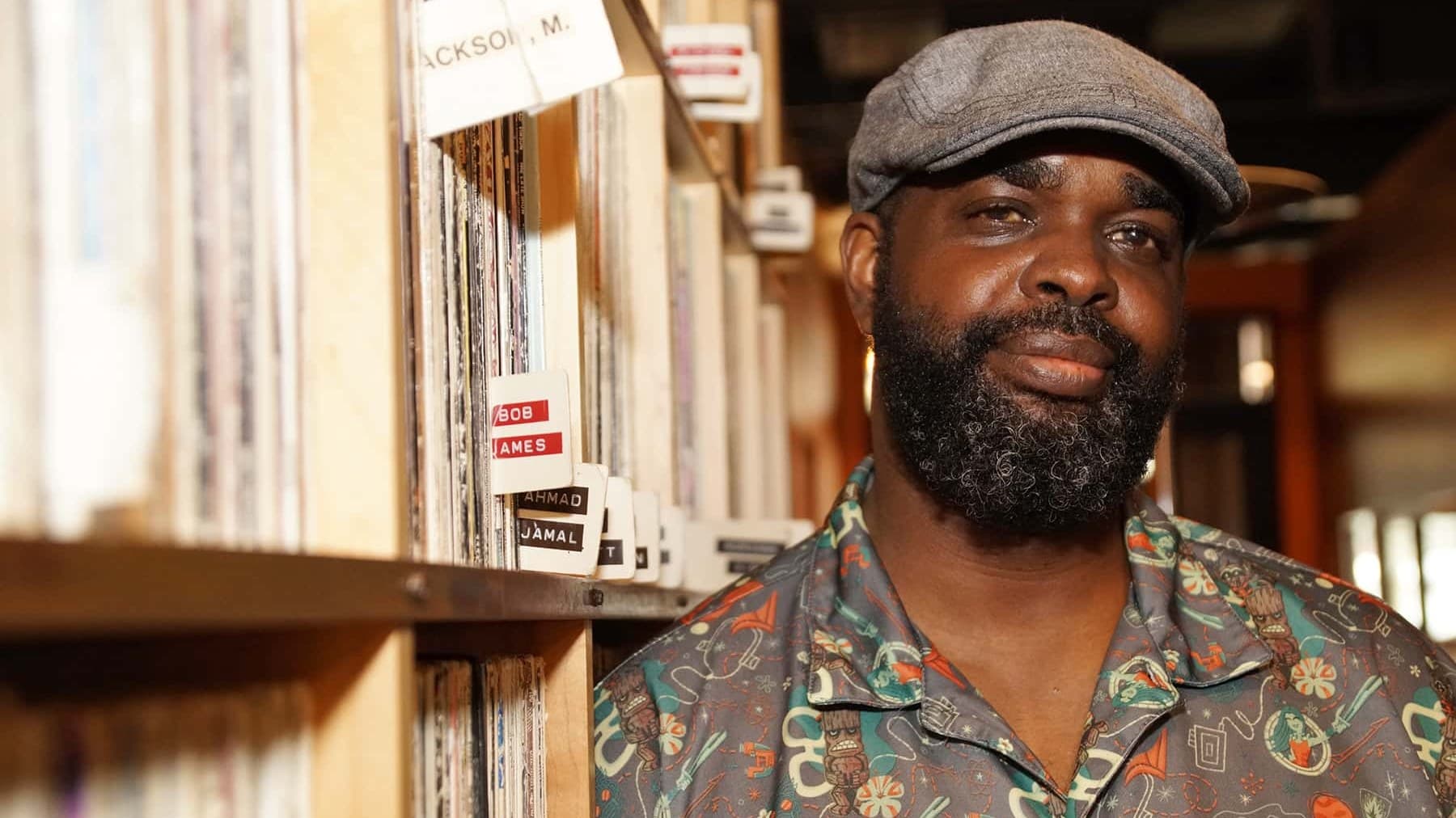Tarik Moody in a record library, beside shelves of vinyl filed under Bob James and Ahmad Jamal